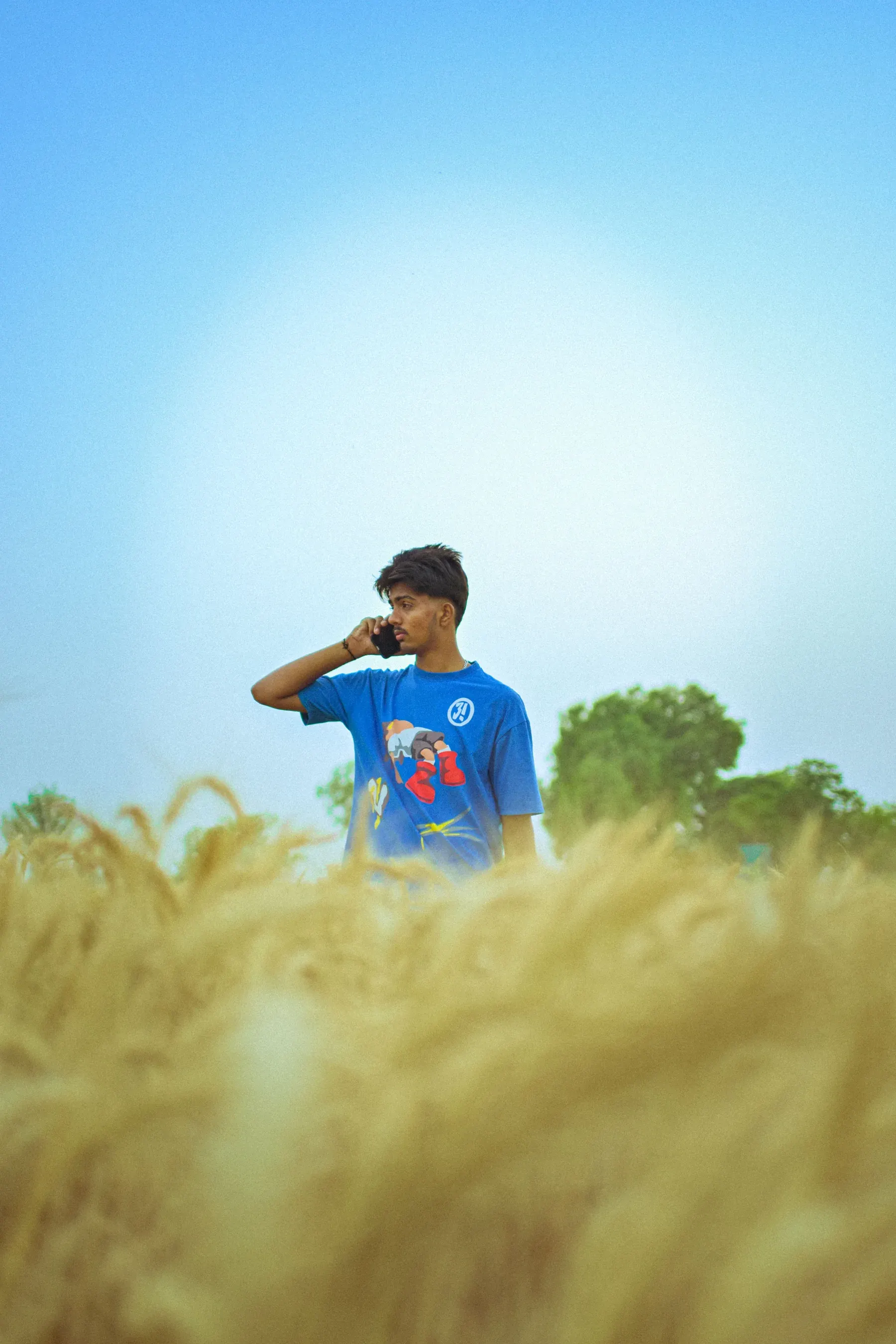 Young Indian farmer using a phone in a field